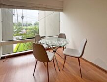 Comedor con mesa de vidrio y vista al Golf de San Isidro