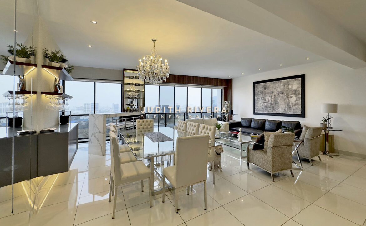 Vista amplia del área social integrada: comedor, barra alta y estar, con grandes ventanales y vista a los cerros y la ciudad.