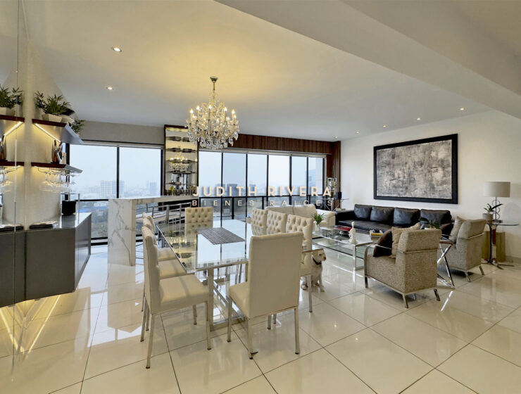 Vista amplia del área social integrada: comedor, barra alta y estar, con grandes ventanales y vista a los cerros y la ciudad.