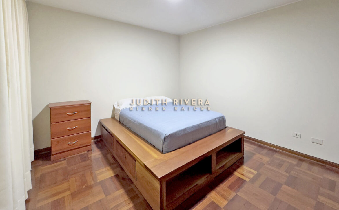 Dormitorio del departamento en alquiler en Surco, con cama, cómoda de madera y paredes claras.