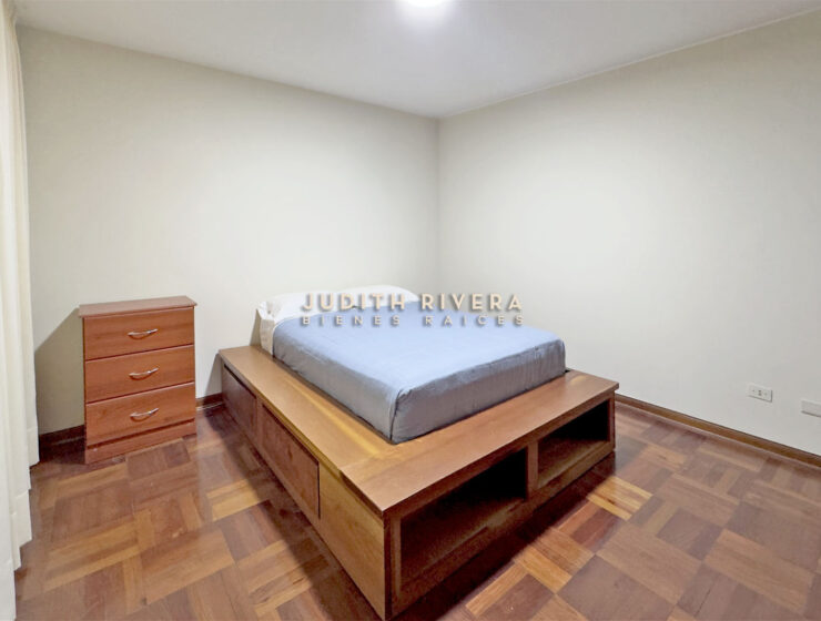 Dormitorio del departamento en alquiler en Surco, con cama, cómoda de madera y paredes claras.