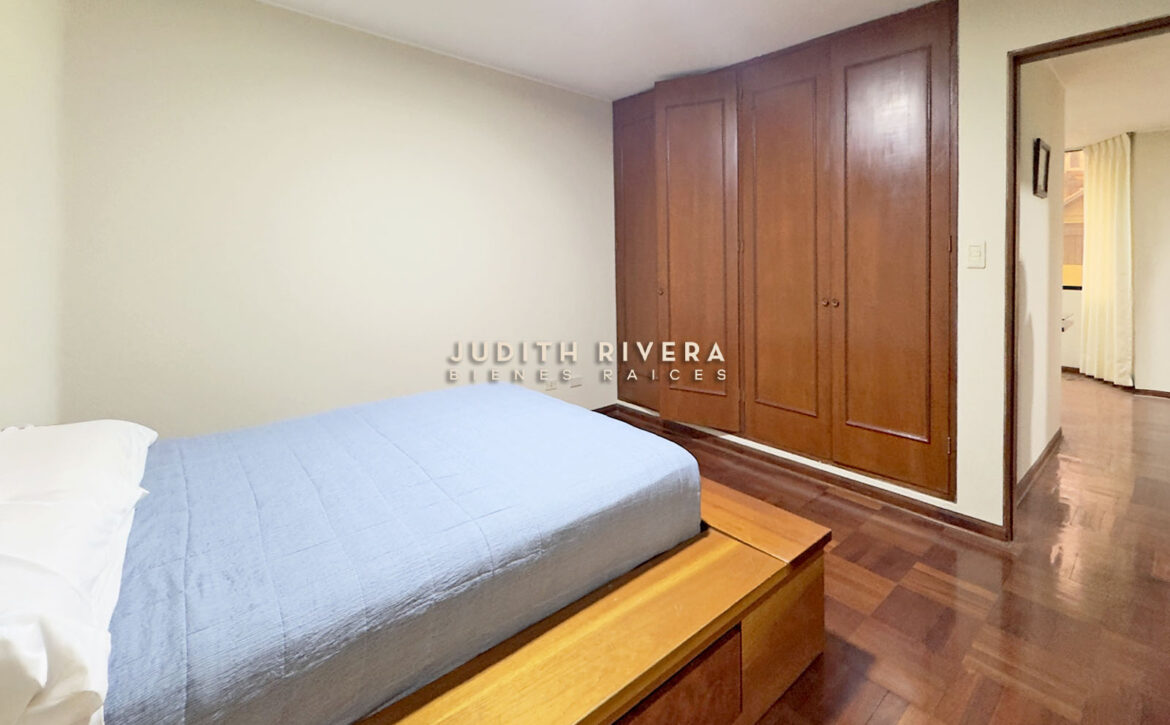 Dormitorio del departamento en Santiago de Surco, con cama y armario empotrado de madera.