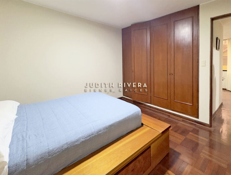 Dormitorio del departamento en Santiago de Surco, con cama y armario empotrado de madera.