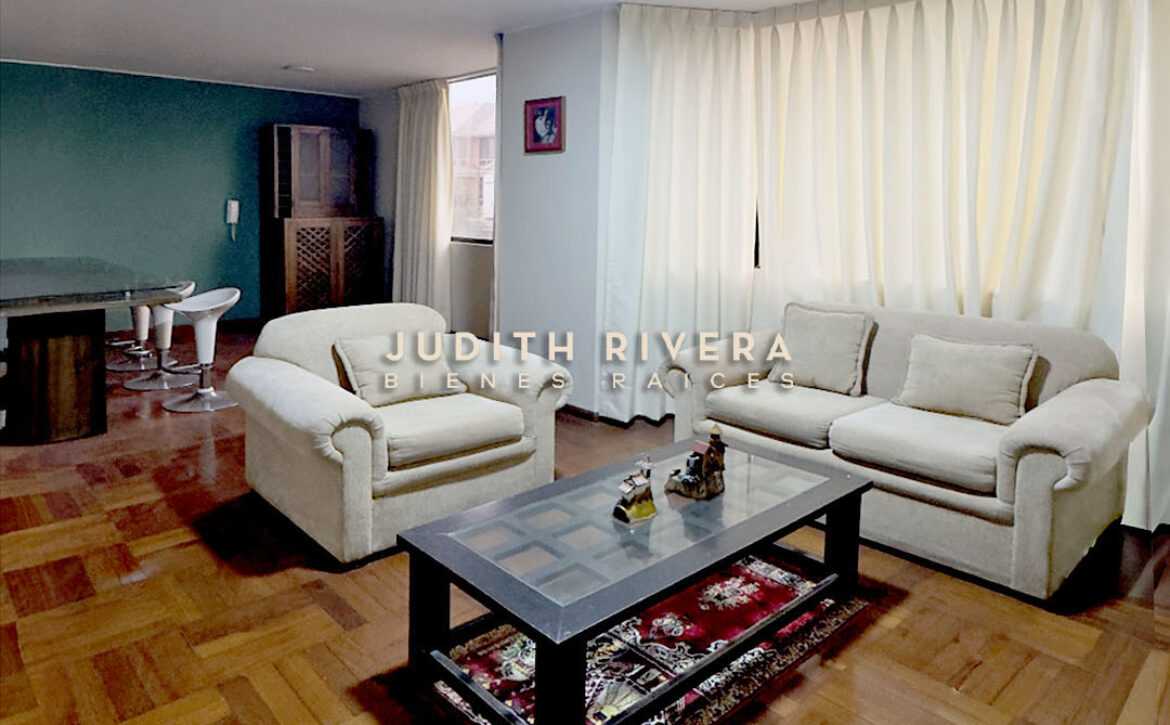 Sala comedor amoblada del departamento en alquiler en Santiago de Surco, con sofás claros, mesa de centro y piso de madera.