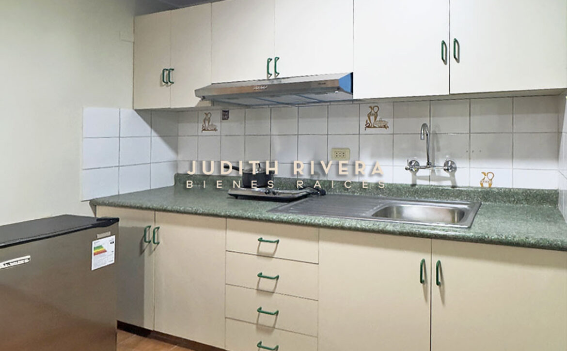 Cocina del departamento en alquiler en Surco, con muebles color crema, encimera verde y lavadero.