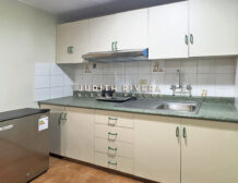 Cocina del departamento en alquiler en Surco, con muebles color crema, encimera verde y lavadero.