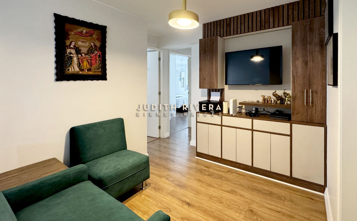Estar familiar con sillones verdes y mueble empotrado de madera con televisor