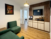 Estar familiar con sillones verdes y mueble empotrado de madera con televisor