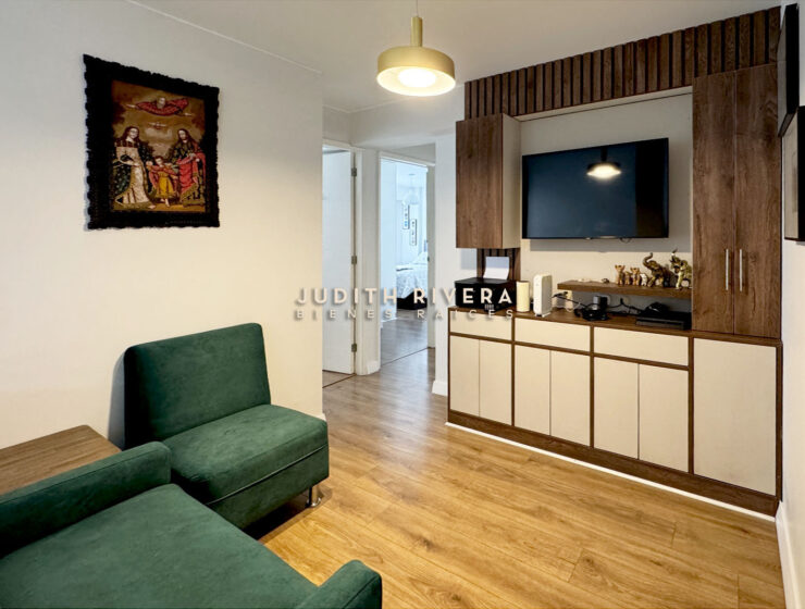 Estar familiar con sillones verdes y mueble empotrado de madera con televisor
