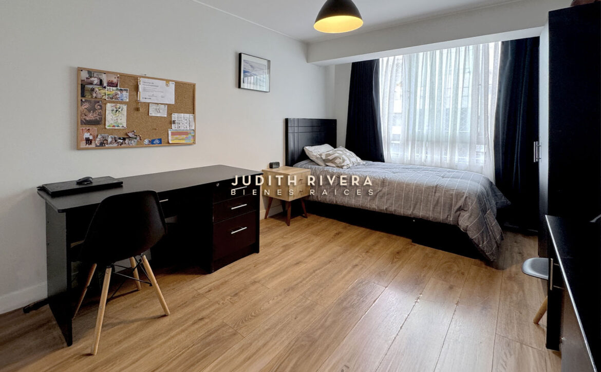 Dormitorio con escritorio de trabajo, cama de dos plazas y ventana amplia con cortinas