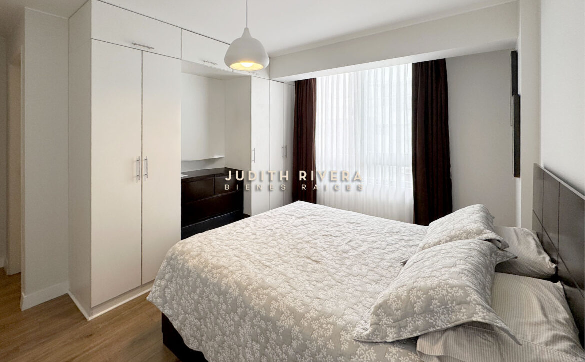 Dormitorio con clóset empotrado blanco de piso a techo y cama de dos plazas
