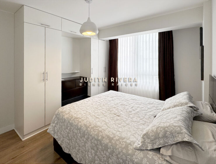 Dormitorio con clóset empotrado blanco de piso a techo y cama de dos plazas